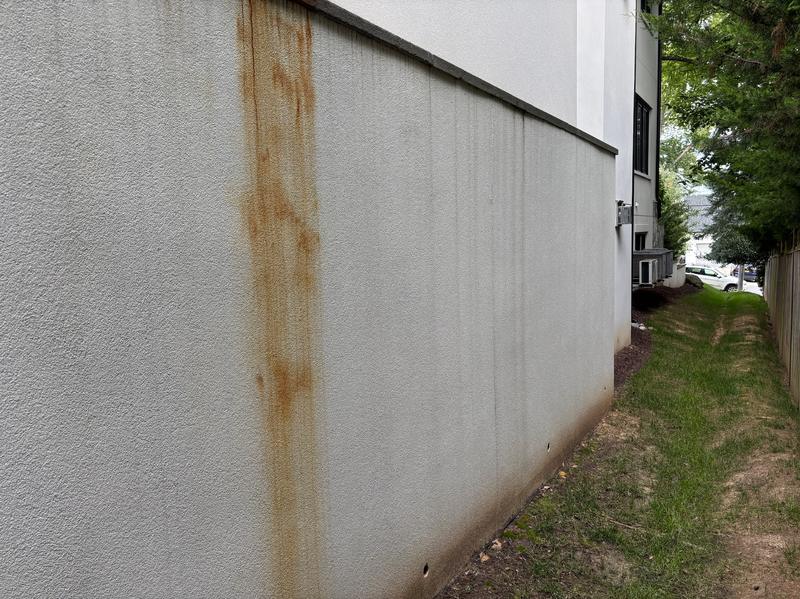 Before: orange rust streak running down a stucco side wall