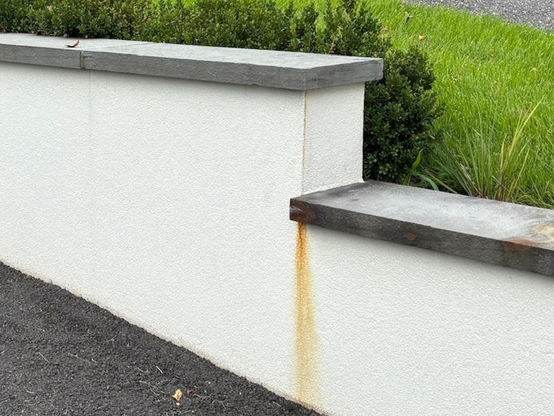 Before: rust drip under a retaining wall capstone along a driveway